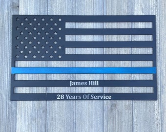Puede incluir: Bandera americana de metal negro con una línea azul, personalizada con el nombre "James Hill" y el texto "28 Years Of Service".