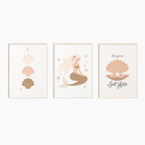 May include: Three framed prints with a mermaid, seashells, and the text "Let your light shine". The mermaid is brown and has blonde hair. The seashells are pink and brown. The background is white.