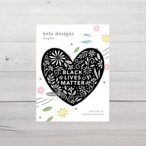 May include: A black and white heart-shaped magnet with floral designs and the text "BLACK LIVES MATTER." The magnet is from "kela designs" and includes the phrase "portion of profits donated."