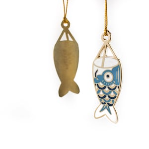 May include: Two gold-colored fish ornaments hanging from gold strings. The fish on the left is plain, while the fish on the right has a blue and white pattern.