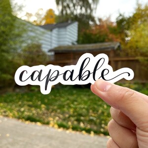 May include: A white sticker with the word "capable" written in black cursive script.