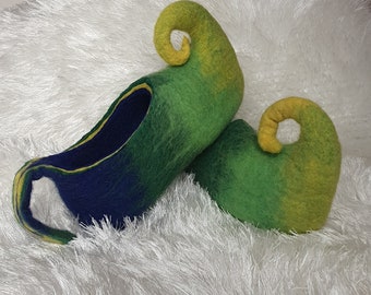 May include: A pair of green, yellow, and blue felt slippers with curled toes. The slippers are made of wool felt and have a soft, comfortable texture.