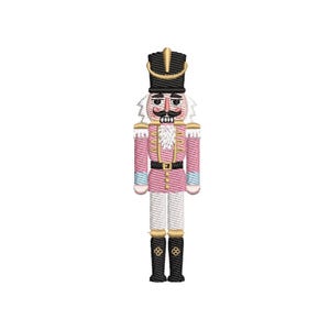 May include: Embroidered pink and black nutcracker soldier with a black hat, gold accents, and white hair. The nutcracker has a black belt, black boots, and is standing upright. A festive holiday decoration.