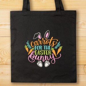 K&ouml;nnte beinhalten: Schwarze Einkaufstasche mit einem gestickten Design aus Karotten, Hasenohren und dem Text "Karotten f&uuml;r den Osterhasen".