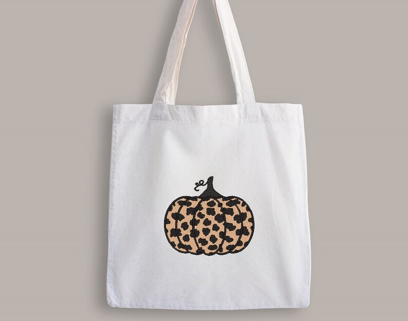 May include: A white tote bag with a black and brown leopard print pumpkin design.