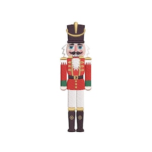 May include: Embroidered image of a toy nutcracker soldier. The nutcracker is wearing a red jacket with gold accents, a black hat, and white hair and beard. The legs are white and the boots are dark brown.