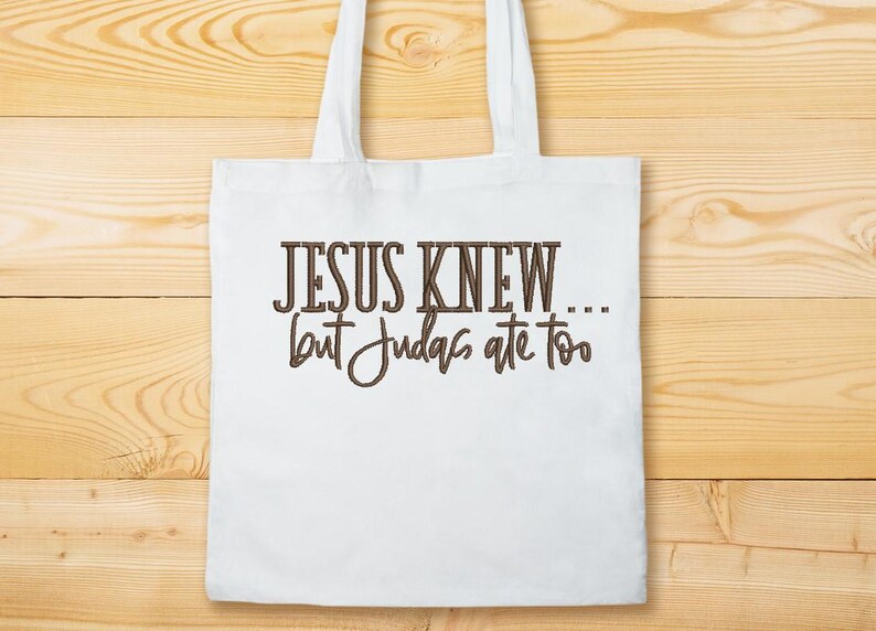 Puede incluir: Bolsa de tela blanca con texto marr&oacute;n que dice "JESUS KNEW... but Judas ate too".