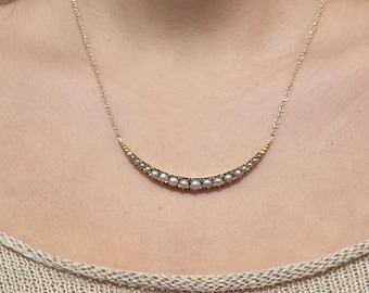 Op de afbeelding: Een gouden ketting met een halve maan ontwerp met kleine parels.