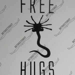 May include: Black and white graphic design featuring an alien creature with the text "FREE HUGS".