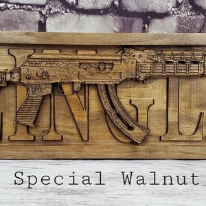May include: A wooden sign with the name "Klingler" carved into it. A 3D carved image of a rifle is displayed above the name. The sign is made of special walnut wood.