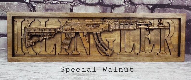 May include: A wooden sign with the name "Klingler" carved into it. A 3D carved image of a rifle is displayed above the name. The sign is made of special walnut wood.