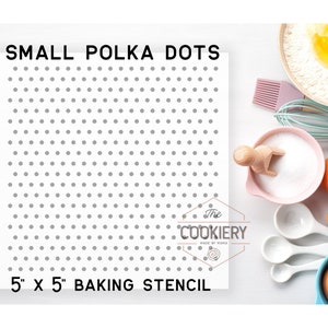 May include: A white baking stencil with a small polka dot pattern. The stencil is 5 inches by 5 inches and is labeled "SMALL POLKA DOTS" and "The Cookiery Made by Mama".