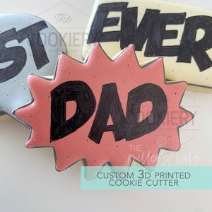 May include: A red and white cookie cutter in the shape of a comic book speech bubble with the word "DAD" written in black inside. The cookie cutter is a 3D printed custom design.