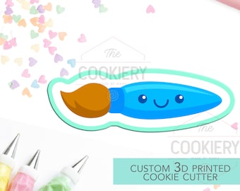 May include: A blue paintbrush cookie cutter with a smiling face. The cutter is 3D printed and has a light blue outline. The cutter is surrounded by colorful heart sprinkles and piping bags.