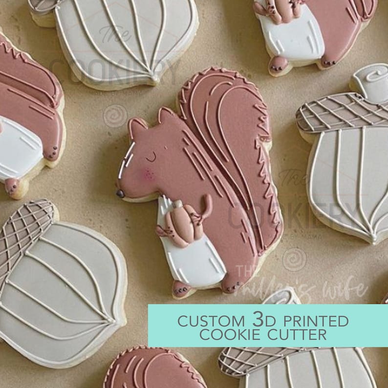 May include: A set of 3D printed cookie cutters featuring a squirrel holding an acorn, an acorn, and a leaf. The cutters are made of white plastic and are designed to create detailed cookies.