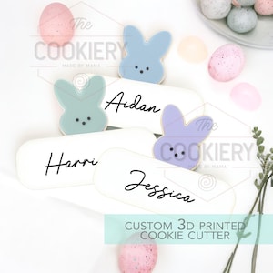 Peut inclure: Quatre emporte-pièces personnalisés en 3D en forme de lapins de Pâques avec les noms "Harri", "Aidan", "Jessica" et "The Cookiery Made by Mama" écrits dessus.