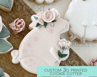 May include: A pink pig cookie cutter with a floral crown and a flower in its hand. The cutter is 3D printed and is part of a set of custom cookie cutters. The text "CUSTOM 3D PRINTED COOKIE CUTTER" is on the image.