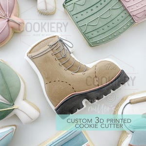 May include: A brown leather boot cookie cutter with a black sole and laces. The cookie cutter is 3D printed and is part of a set of custom cookie cutters. The text "CUSTOM 3D PRINTED COOKIE CUTTER" is visible in the image.