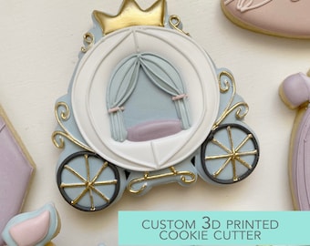May include: A 3D printed cookie cutter in the shape of a blue and white carriage with a gold crown on top. The carriage has a white interior with a light blue canopy and a purple seat. The cookie cutter is labeled "CUSTOM 3D PRINTED COOKIE CUTTER".