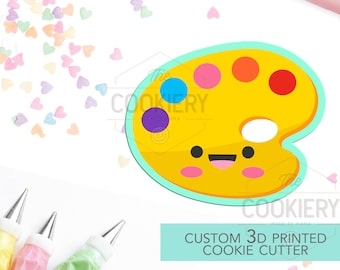 May include: A yellow and blue 3D printed cookie cutter shaped like a paint palette with a smiling face. The cutter has five paint wells with different colored paint drops.  Custom 3D Printed Cookie Cutter.