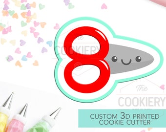 May include: A custom 3D printed cookie cutter in the shape of the number 8 with a cute cartoon face. The cutter is red and gray with a turquoise outline. The cutter is on a white background with colorful heart sprinkles.