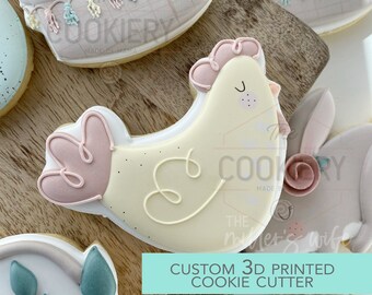 May include: A 3D printed cookie cutter in the shape of a yellow chick with pink accents. The cutter is designed for making cookies. The text "CUSTOM 3D PRINTED COOKIE CUTTER" is visible in the image.