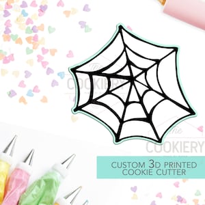 May include: A black and white 3D printed spiderweb cookie cutter. The cutter is on a white background with colourful sprinkles. The text "CUSTOM 3D PRINTED COOKIE CUTTER" is on a light blue background.