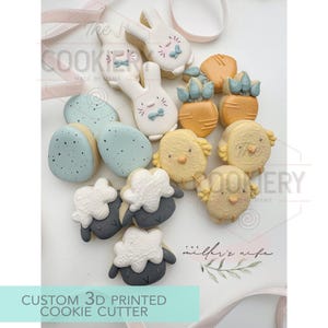 May include: An assortment of Easter-themed cookies, including bunnies, carrots, chicks, eggs, and sheep. The cookies are decorated with pastel colors and intricate details. The text "CUSTOM 3D PRINTED COOKIE CUTTER" is visible.