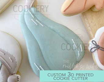 May include: A 3D printed cookie cutter in the shape of a light blue gourd with white lines. The text "CUSTOM 3D PRINTED COOKIE CUTTER" is on a green background.