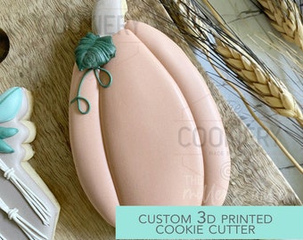May include: A light pink pumpkin cookie cutter with a green leaf on top. The cookie cutter is 3D printed and is a custom design. The text "CUSTOM 3D PRINTED COOKIE CUTTER" is on a teal background.