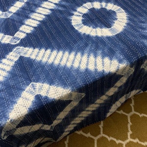 May include: A blue and white kantha quilt with a tie-dye pattern. The quilt is made of cotton and has a hand-stitched design.