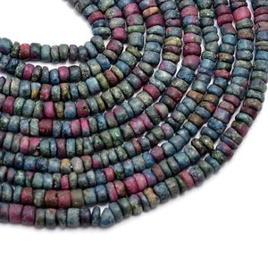May include: A strand of blue and pink gemstone beads. The beads are round and have a rough, textured surface. The strand is made up of multiple rows of beads, creating a layered effect.