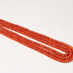 May include: A long strand of bright orange coral beads. The beads are round and uniform in size, creating a smooth and continuous line.
