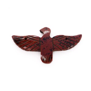 May include: A red, brown, and black carved stone eagle with outstretched wings.