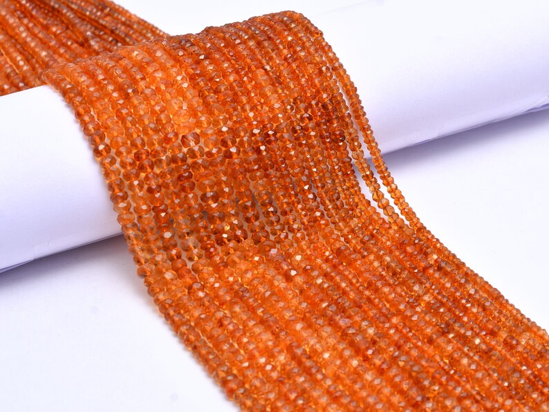 May include: A strand of orange gemstone beads. The beads are faceted and have a slightly irregular shape. The beads are strung on a clear thread and are ready to be used for jewelry making.