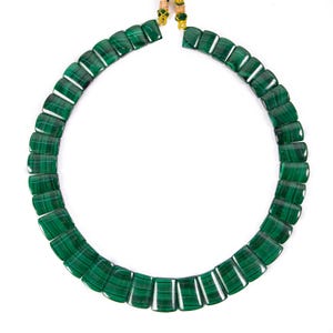 May include: A necklace composed of rectangular, polished malachite stones in varying shades of green. The stones are strung together to form a circular shape, with gold-colored accents at the clasp. The necklace is displayed against a white background.
