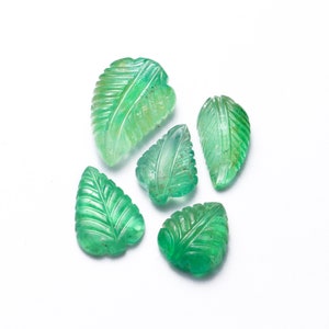 May include: Five green emerald gemstone leaf carvings. The leaves are carved with detailed veins and are a light to medium green color.