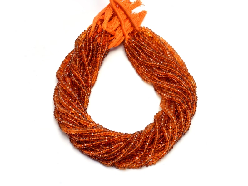 May include: A strand of orange gemstone beads, likely carnelian, arranged in a circle. The beads are faceted and have a glossy finish.