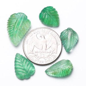 May include: Five green gemstone leaf-shaped beads, each with a carved vein pattern, are arranged in a circle around a US quarter dollar coin. The beads are approximately the size of the coin.