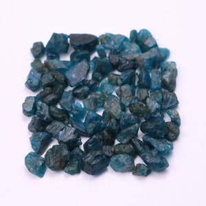 May include: A collection of blue-green gemstone chips. The chips are rough and have a variety of shapes and sizes.