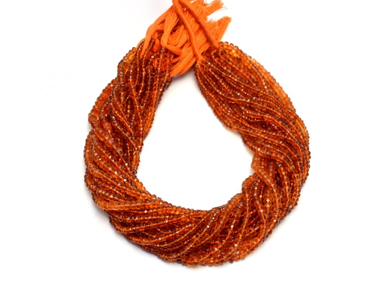 May include: A strand of orange gemstone beads, likely carnelian, arranged in a circle. The beads are faceted and have a glossy finish.
