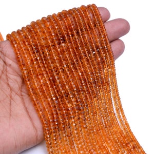 May include: A strand of orange gemstone beads. The beads are faceted and have a shiny, translucent finish. The beads are strung on a thin wire and are approximately 4mm in diameter.