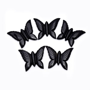 May include: Six black carved butterfly charms. The butterflies are intricately detailed and have a polished finish.