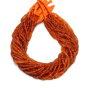 May include: A strand of orange gemstone beads, likely carnelian, arranged in a circle. The beads are faceted and have a glossy finish.