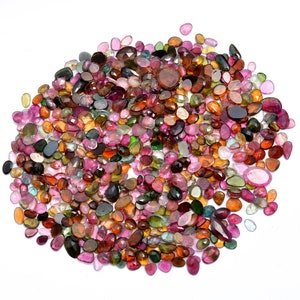 May include: A large collection of colorful, faceted gemstones in various shades of pink, green, brown, and black. The gemstones are oval-shaped and have a smooth, polished finish.