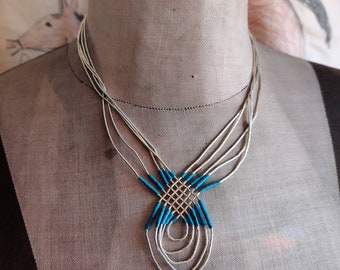 Liquid silver necklace with several strands and turquoise colored block heishe,