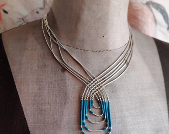 Liquid silver necklace with several strands and turquoise colored block heishe,