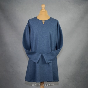 May include: A long-sleeved tunic in a dark blue color with a round button at the neckline. The tunic has a simple design and is made of a soft, comfortable fabric.