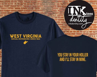 May include: A navy blue t-shirt with a gold graphic print of the state of West Virginia and the text "West Virginia Social Distancing Since 1863". The back of the shirt has the text "You stay in your holler and I'll stay in mine."