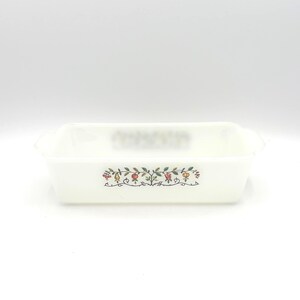 May include: A rectangular white milk glass baking dish featuring a central horizontal band decorated with a colorful botanical pattern of small fruits, berries, and green leaves connected by thin black scrolling vines on the front exterior.